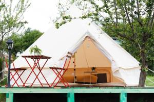 a white tent with a chair and a table at Glamping Cisnadioara in Cisnădioara