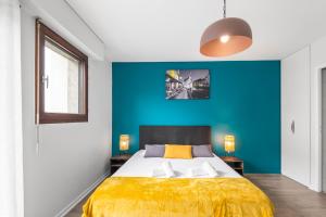 - une chambre avec un grand lit et un mur bleu dans l'établissement Terraces of Bonlieu - the nest, à Annecy