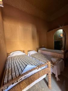 2 camas en una habitación con espejo en Riad Nkob en Nkob