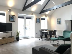 a living room with a tv and a table with chairs at Modern~ Reverse Level~2 bed~Townhouse~Central~Penzance in Penzance