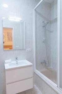 a white bathroom with a shower and a sink at El Pez Volador by Gades Gestión in Cádiz