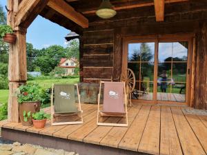 twee stoelen op een veranda van een hut bij Miejsce po Dworze in Polana