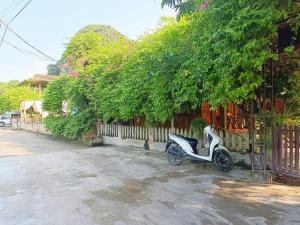 una moto blanca estacionada junto a una valla en Tam Coc Sunshine Homestay en Ninh Binh