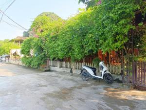 a white scooter parked next to a fence at Tam Coc Sunshine Homestay in Ninh Binh