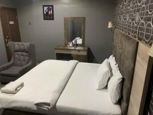 a bedroom with a bed and a chair and a mirror at Hotel Fountain Blu in Abeokuta