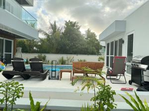 un patio con sillas y una parrilla junto a una casa en Ocean Pearl - A brand new one bedroom with pool, walkable distance to sunset beach en Long Bay Hills