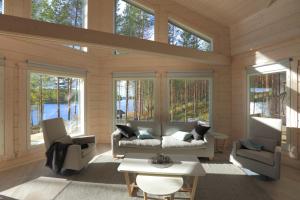 ein Wohnzimmer mit Sofa, Stühlen und Fenstern in der Unterkunft Villa Tukkilahti 4 in Savonranta