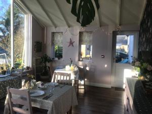 a dining room with a table and chairs and windows at Netherdene Country House Bed & Breakfast in Troutbeck