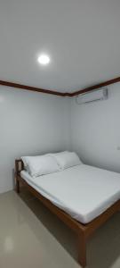 een bed in een kamer met een witte muur bij Casa Victoria Pension House- Star Challenger in Somosomo