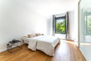 Un dormitorio blanco con una cama grande y una ventana en Spacieuse Maison à 15 min de la Tour Eiffel, en Suresnes