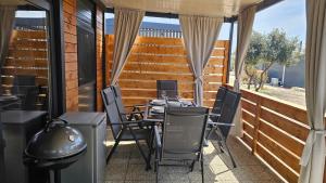 a patio with a table and chairs and a grill at CHARTA mobile home Roko in Pirovac