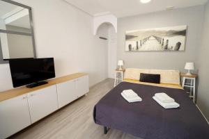 1 dormitorio con 1 cama y TV de pantalla plana en Apartment Blanco - Vina Mar III, en La Mata