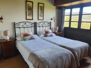 two twin beds in a bedroom with two windows at Complejo turístico Las Mimosas del Nalon, LOS NOVALES in San Juan de la Arena