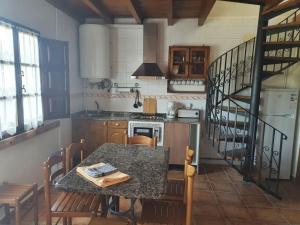una cocina con una mesa con sillas y una escalera en Complejo turístico Las Mimosas del Nalon, LOS NOVALES, en San Juan de la Arena
