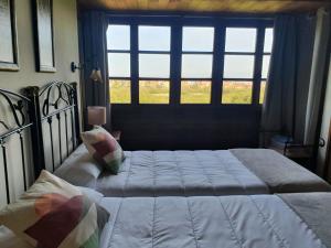 Un dormitorio con una cama grande y una ventana en Complejo turístico Las Mimosas del Nalon, LOS NOVALES en San Juan de la Arena