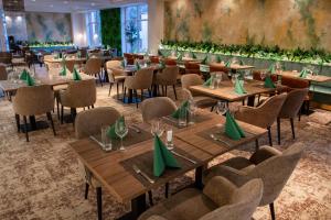 a restaurant with wooden tables and chairs with green napkins at Hotel Azur Premium in Si&oacute;fok