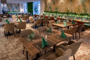 un restaurante con mesas de madera y sillas con servilletas verdes en Hotel Azur Premium, en Siófok