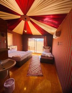 a bedroom with two beds and a large window at Sunset colors camp in Wadi Rum