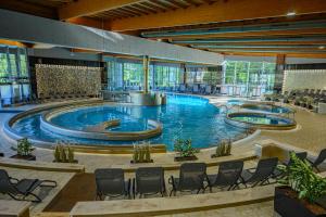 ein großer Pool in einem Gebäude mit Stühlen um ihn herum in der Unterkunft Hotel Azur Premium in Siófok