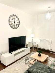 a living room with a large television and a clock on the wall at Captivating 2-Bed Apartment in Maidstone in Maidstone