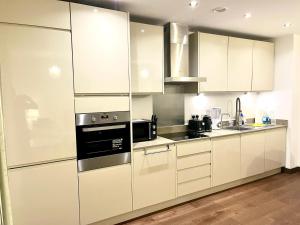a kitchen with white cabinets and a black appliance at Captivating 2-Bed Apartment in Maidstone in Maidstone