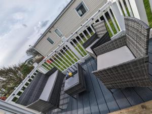 a deck with wicker chairs and stairs on a house at Lyndean - Skipsea Sands in Skipsea
