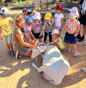 a woman petting a cow in front of a group of children at Séjour à la ferme in Jouques