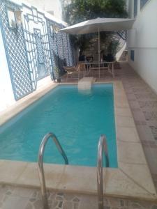 - une piscine bleue avec un parasol et une table dans l'établissement Dar Sarra, à Sousse