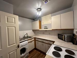 cocina pequeña con armarios blancos y fogones horno superior en City Lights Apartment en Edimburgo
