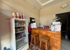 a kitchen with a counter with a refrigerator and two stools at Steze Guesthouse Syariah Telanaipura in Jambi
