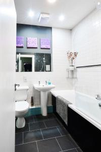 a bathroom with a sink and a toilet and a bath tub at Satori Serviced Apartments in Manchester