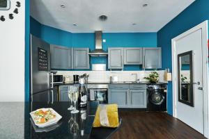 een keuken met blauwe muren en een tafel met wijnglazen bij Satori Serviced Apartments in Manchester