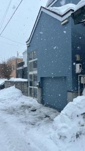 un edificio azul con un garaje en la nieve en SecondHouse Otaru Garden en Otaru
