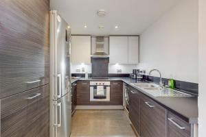a kitchen with wooden cabinets and a stainless steel refrigerator at Stylish 2Bed penthouse with terrace in Canary Wharf in London