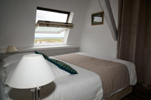 um quarto com uma cama com um candeeiro e uma janela em La Cathédrale de Sel em Batz-sur-Mer
