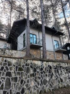 una casa sentada en la parte superior de una pared de piedra en Apartmani Jelena, en Vrnjačka Banja