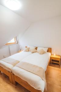 Rogla Alpina Residence في زريس: سريرين في غرفة بجدران بيضاء وأرضية خشبية