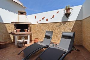 2 chaises assises sur une terrasse avec cheminée dans l'établissement Casa La Herradura, à Telde