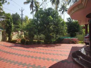 a red brick walkway with trees and palm trees at Ashiaana Homestay in Trichūr