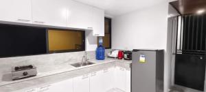 a white kitchen with a sink and a refrigerator at Casa Victoria Pension House-Star Maria in Somosomo