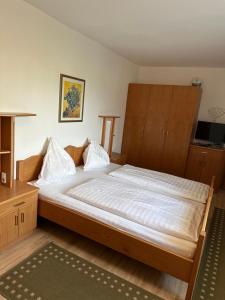 um quarto com uma cama grande e lençóis brancos em Leo's Pension em Bad Schallerbach