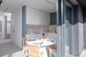 eine Küche und ein Esszimmer mit einem weißen Tisch und Stühlen in der Unterkunft HEVENIA POGORZELICA - APARTAMENT 1 in Pogorzelica + 14 Fotos