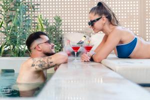 Un uomo e una donna seduti in piscina di Sabbia Mini Pool Suites a Preveza