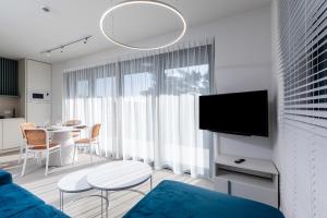 ein Wohnzimmer mit einem blauen Sofa und einem TV in der Unterkunft HEVENIA POGORZELICA - APARTAMENT 1 in Pogorzelica
