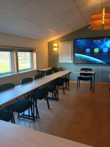 una clase con mesas, sillas y una pantalla grande en Vandrarhem Dahléns en Axvall