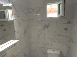 a white bathroom with a toilet and a window at Digkas Apartments in Kato Korakiana