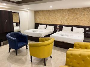 een hotelkamer met 2 bedden en een gele stoel bij Diviyum Manor in Port Blair