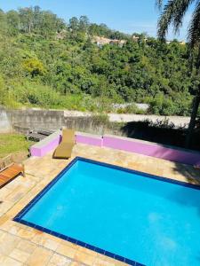 duży niebieski basen na wyłożonym kafelkami patio w obiekcie Chácara Aconchegante com Piscina e Salão de Festas w mieście Embu