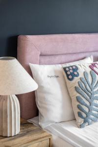 łóżko z różowym zagłówkiem z poduszkami i lampą w obiekcie Przystań Stegna w Stegnie