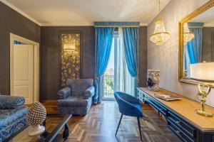 a living room with a desk and blue chairs at Grand Hotel Villa Politi in Siracusa